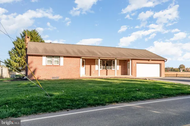 a view of yellow house with a big yard and large tree