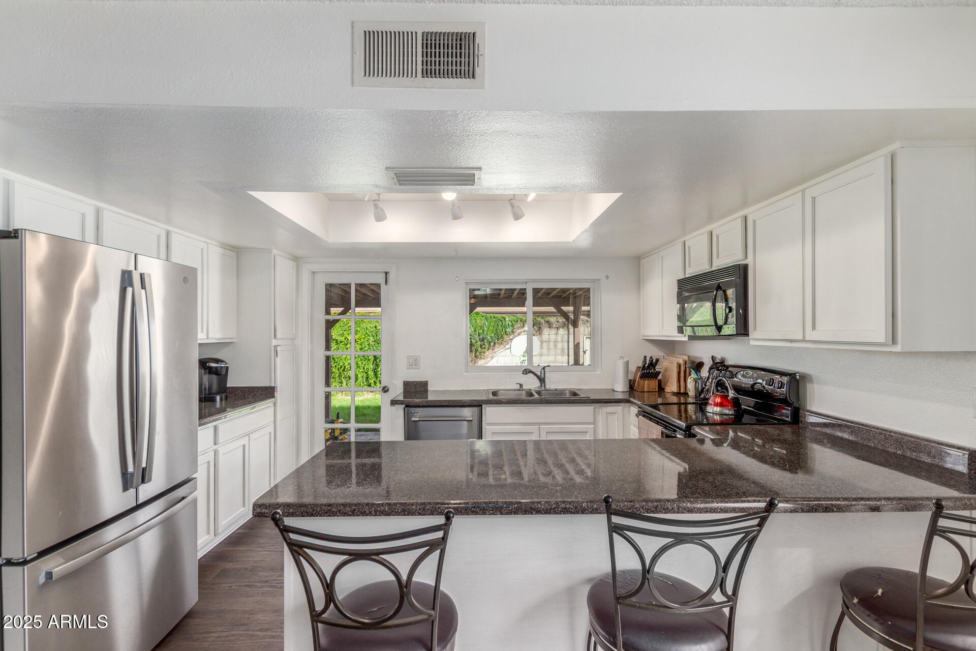 4732 West Davis Road Glendale, AZ 85306 - Photo 12 of 38 a kitchen with stainless steel appliances granite countertop a refrigerator a sink a stove and white cabinets
