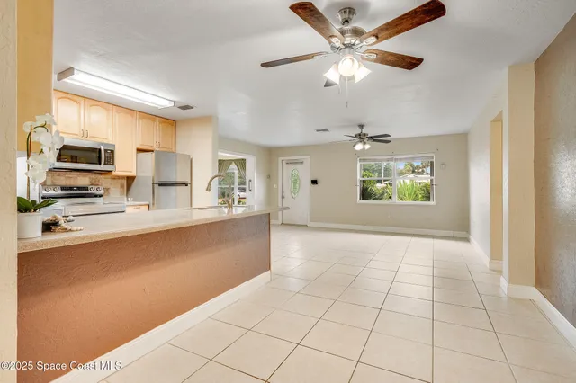 a view of an empty room with window and chandelier fan