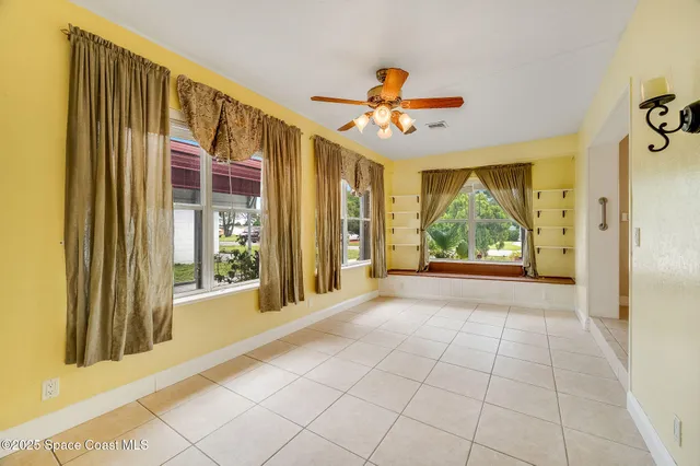 an empty room with a window and chandelier fan