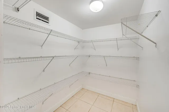 an empty room with a chandelier fan and windows