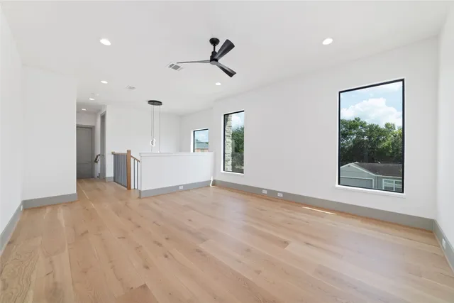 a view of an empty room with a window and wooden floor