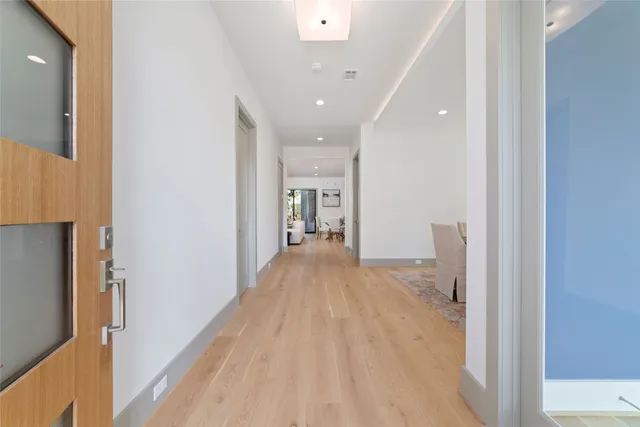a view of a hallway with wooden floor and a refrigerator