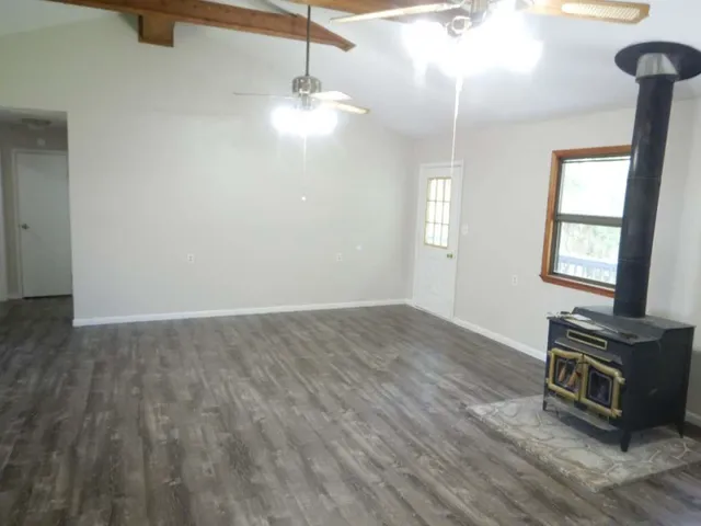 a view of an empty room with window and wooden floor