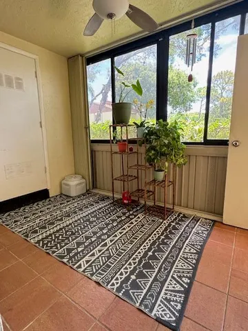 a view of an empty room with window and chandelier fan