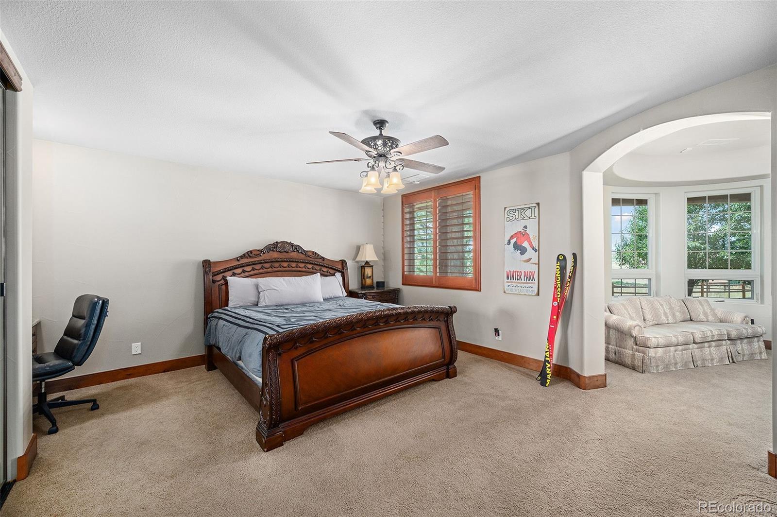 5740 Lambert Ranch Trail Sedalia, CO 80135 - Photo 31 of 48 a spacious bedroom with a bed and a chandelier
