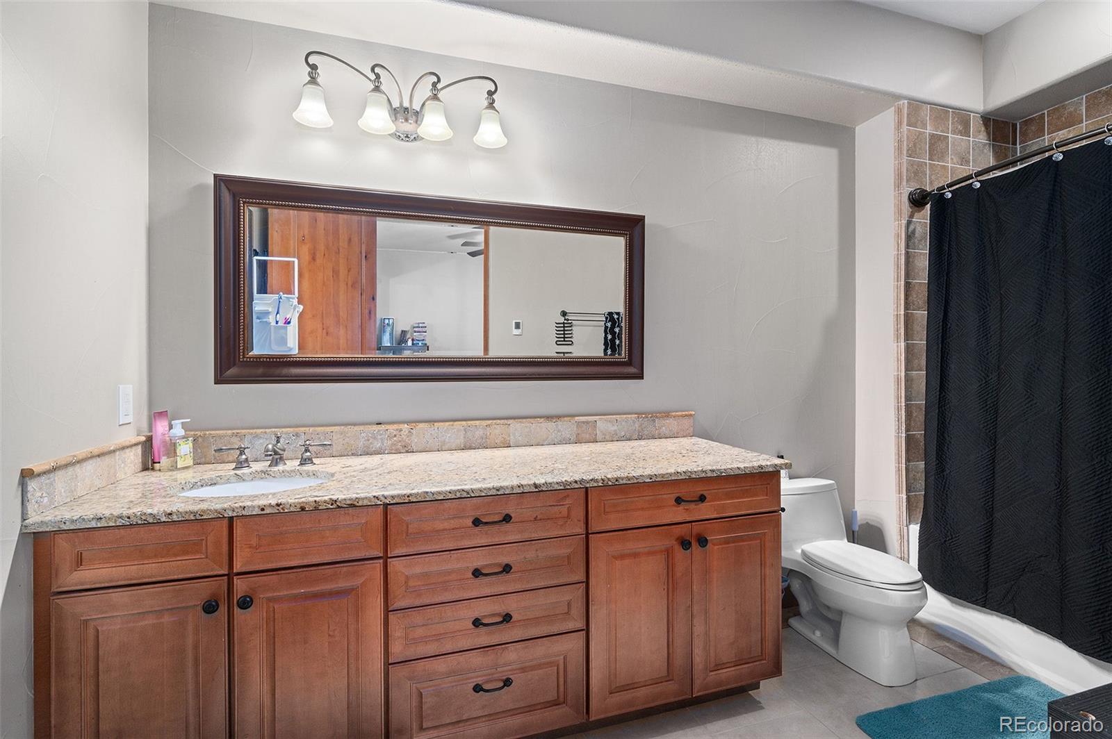 5740 Lambert Ranch Trail Sedalia, CO 80135 - Photo 35 of 48 a bathroom with a granite countertop toilet sink and mirror