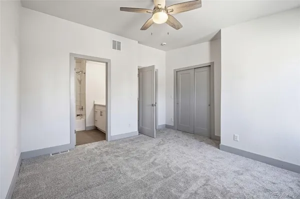 an empty room with a ceiling fan and a bathroom