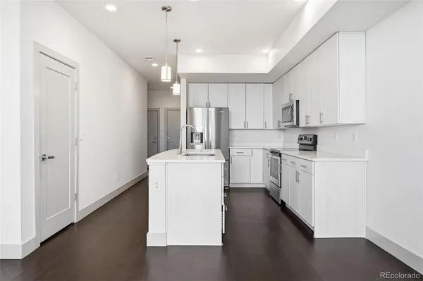a kitchen with a refrigerator a stove top oven a sink dishwasher and white cabinets with wooden floor