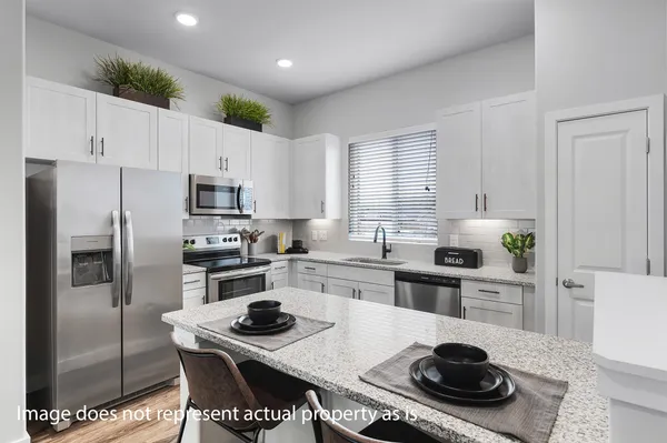 a kitchen with a sink a stove a refrigerator and white cabinets