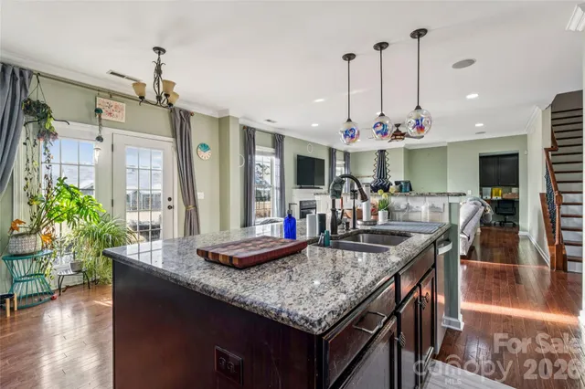 a kitchen island with granite countertop a table chairs and a chandelier
