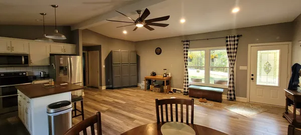 a kitchen that has a refrigerator a stove a sink dishwasher a dining table and chairs with wooden floor