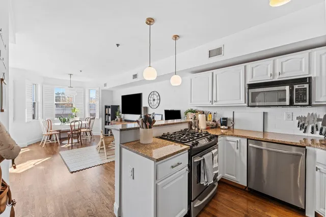 a kitchen with granite countertop a sink a stove top oven a counter space and cabinets