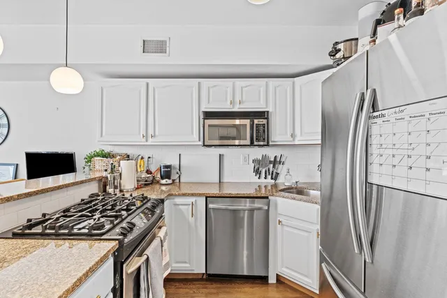 a kitchen with stainless steel appliances a refrigerator sink and white cabinets