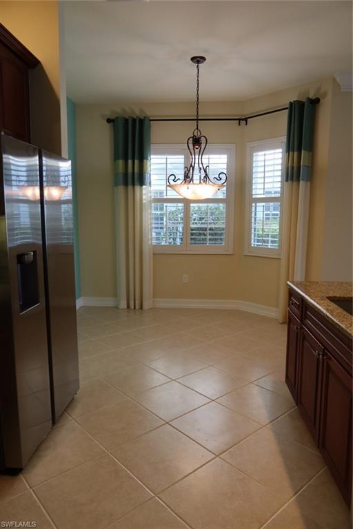 7168 Lemuria Circle, Unit 1701 Naples, FL 34109 - Photo 11 of 39 Dining area featuring a bay window with plantation shutters, a decorative ceiling fixture, and neutral-toned tile flooring