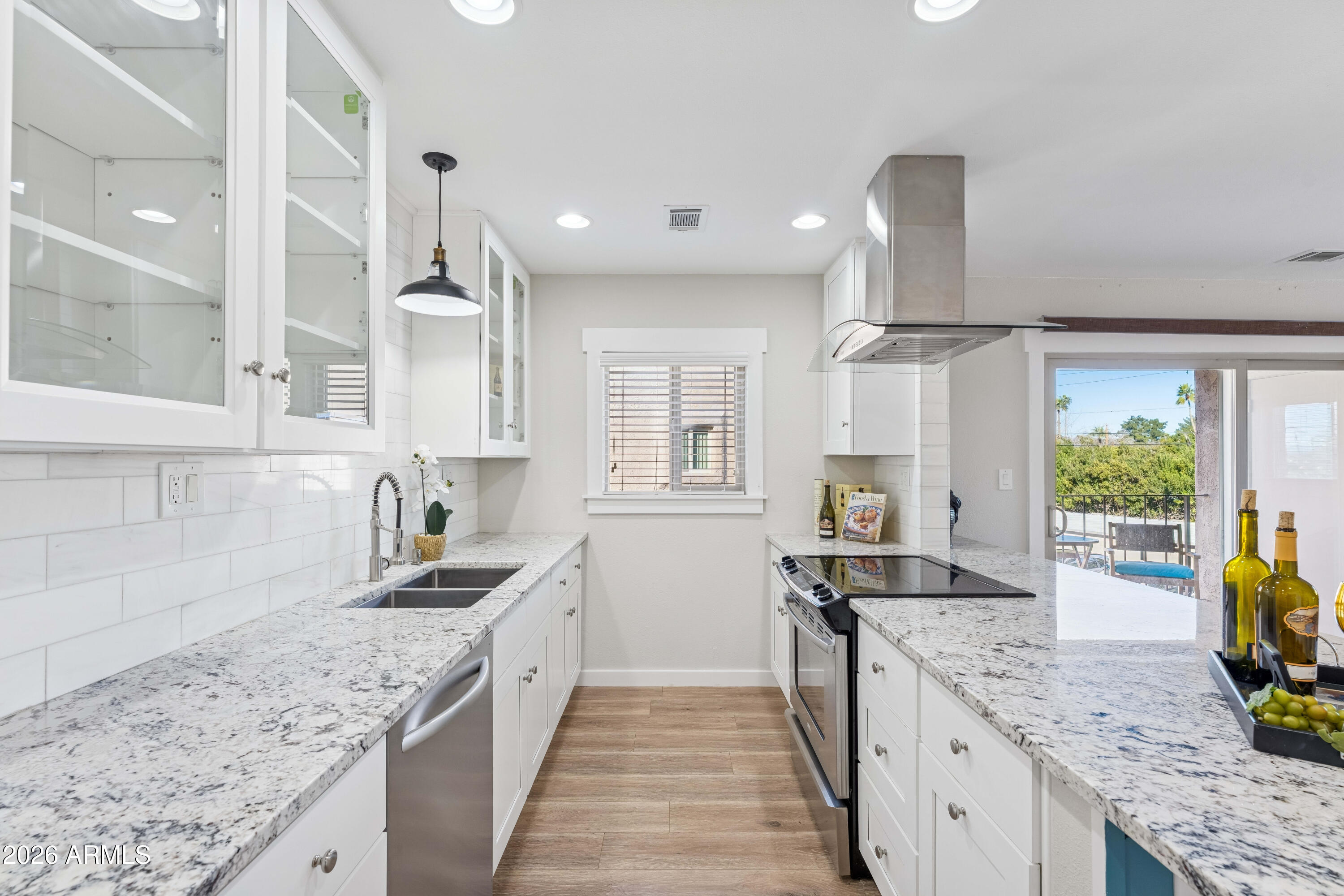 a kitchen with granite countertop kitchen island stainless steel appliances a sink stove and cabinets