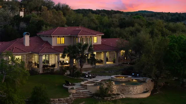 a view of a large pool with lawn chairs under an umbrella