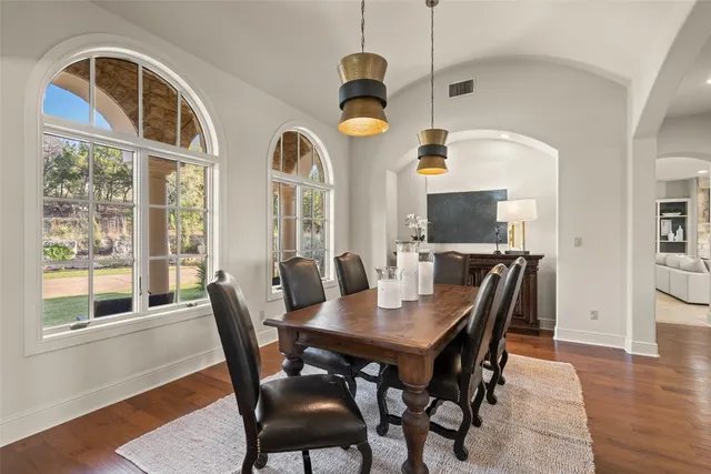 a dining room with wooden floor a chandelier a wooden table and chairs