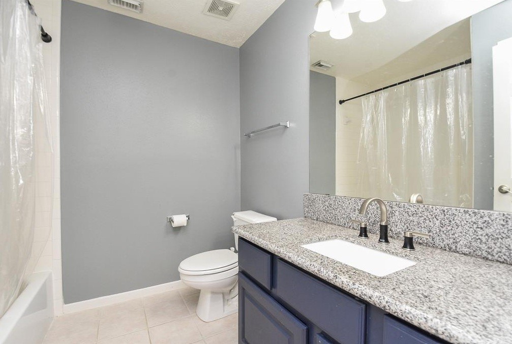16522 Champions Cove Circle Spring, TX 77379 - Photo 23 of 30 a bathroom with a granite countertop sink a toilet and a mirror