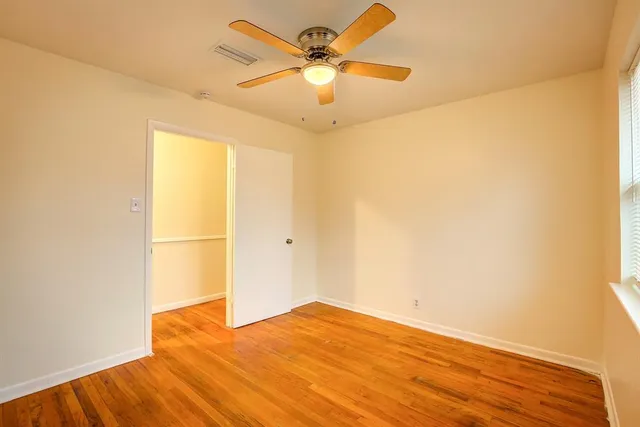 a view of a big room with wooden floor and a chandelier fan
