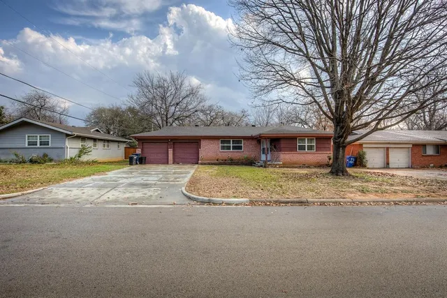 a view of a house with a yard and a large tree