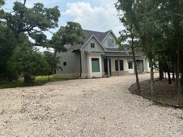 a front view of a house with a dirt yard and a large tree