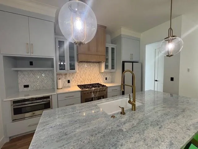 a kitchen with stainless steel appliances granite countertop a sink a stove and a refrigerator