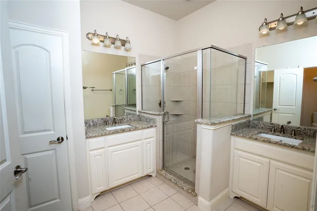 a bathroom with a double vanity sink mirror and shower