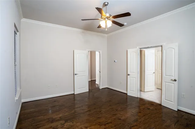 an empty room with wooden floor and a ceiling fan