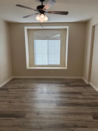 a view of a hallway with wooden floor and a bathroom