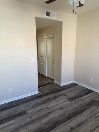 an empty room with wooden floor fan and windows