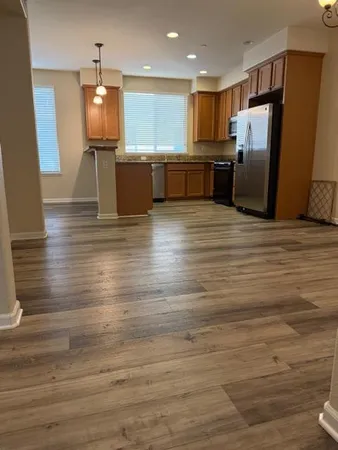 a kitchen with stainless steel appliances wooden floor dining table chairs and wooden floor