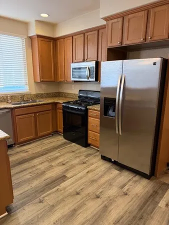 a kitchen with granite countertop a refrigerator and a stove top oven