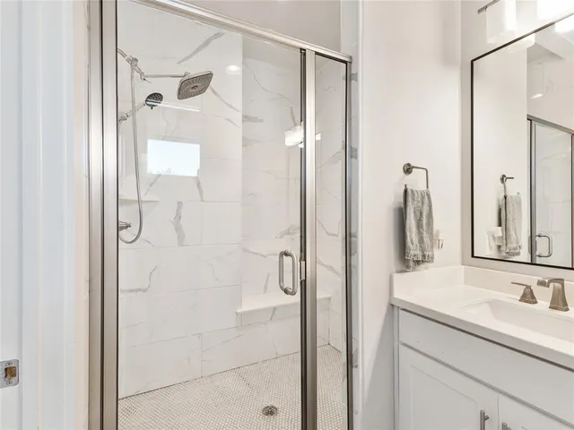 a bathroom with a granite countertop shower sink vanity and mirror