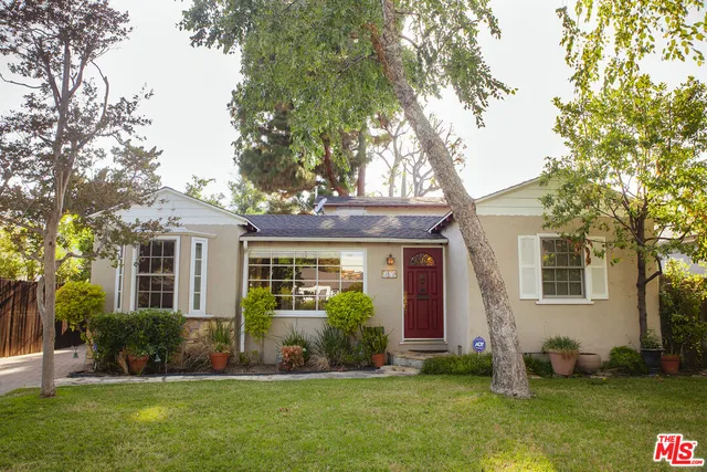a front view of a house with a yard and trees