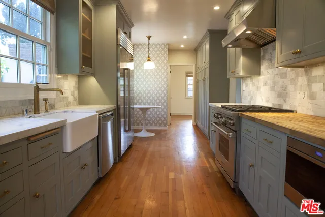 a kitchen with stainless steel appliances granite countertop a lot of counter space and wooden floors