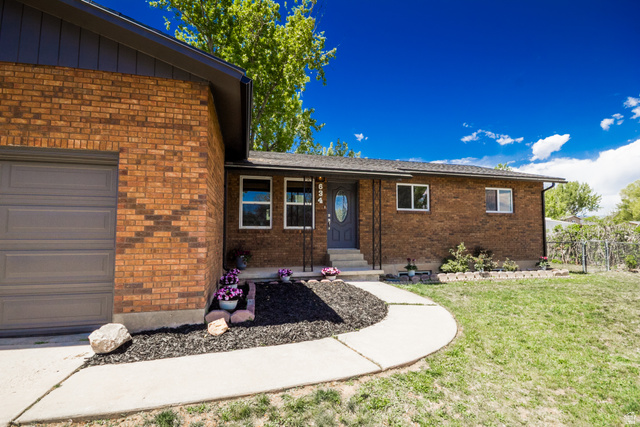 634 South 2100th Street West Vernal, UT 84078 - Photo 54 of 71 Brick exterior featuring a gray paneled garage door and a complementary gray entry door with an oval glass insert