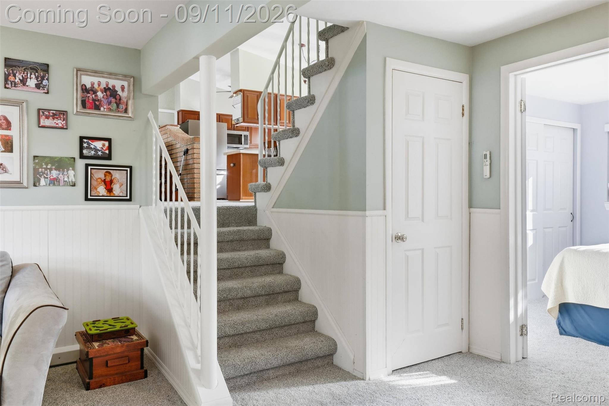 16799 Farmington Road Livonia, MI 48154 - Photo 32 of 71 Carpeted staircase with white balusters, leading to an upper level featuring a kitchen with wood cabinetry and stainless steel appliances