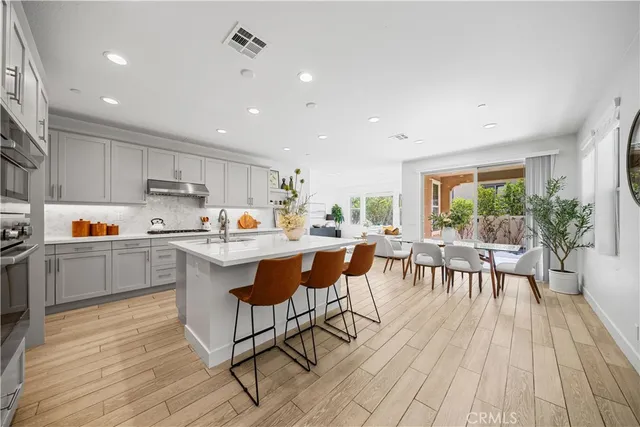 a kitchen with stainless steel appliances kitchen island granite countertop a table chairs and a refrigerator