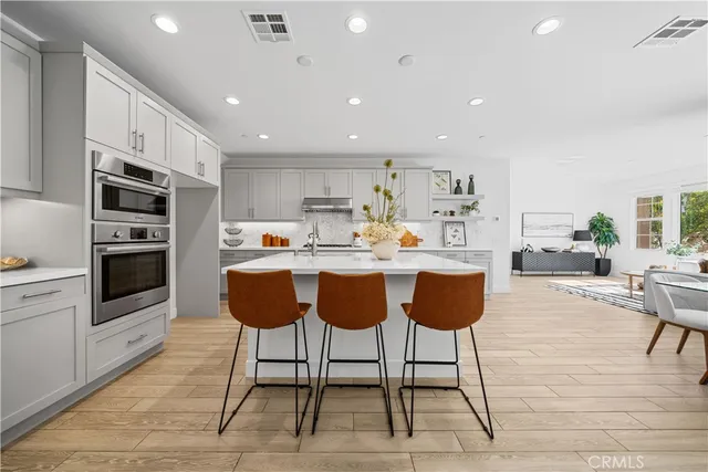 a open kitchen with white cabinets and stainless steel appliances with wooden floor