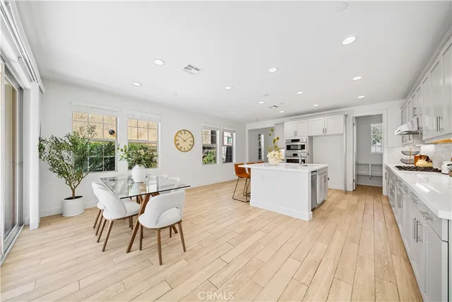 a kitchen with a dining table chairs wooden floor appliances and cabinets