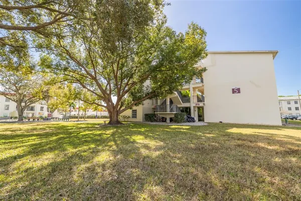 a view of a building with a big yard and large trees