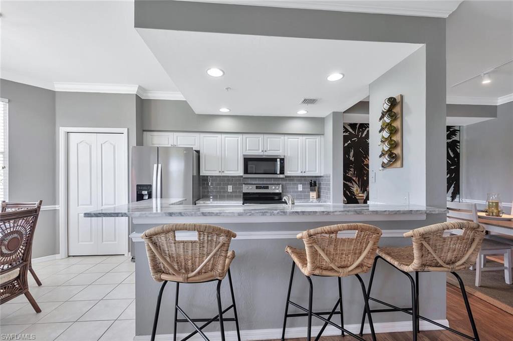 8600 Cedar Hammock Circle, Unit 1313 Naples, FL 34112 - Photo 7 of 48 a kitchen with stainless steel appliances kitchen island granite countertop a dining table chairs and a refrigerator
