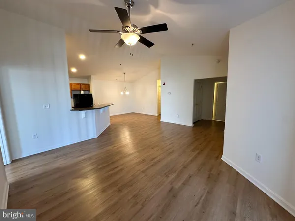 a view of an empty room with wooden floor and a ceiling fan