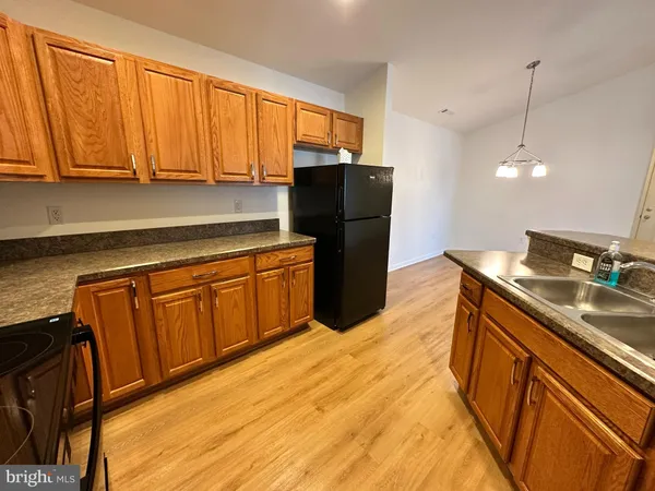 a kitchen with stainless steel appliances granite countertop a refrigerator a sink dishwasher and wooden cabinets