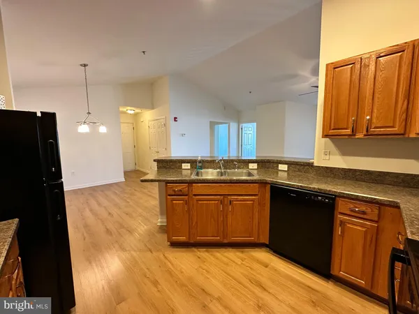 a kitchen with stainless steel appliances granite countertop a refrigerator a sink a stove and wooden floors