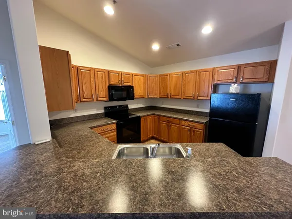 a kitchen with stainless steel appliances kitchen island granite countertop a refrigerator a stove a sink a washer dryer and a dining table