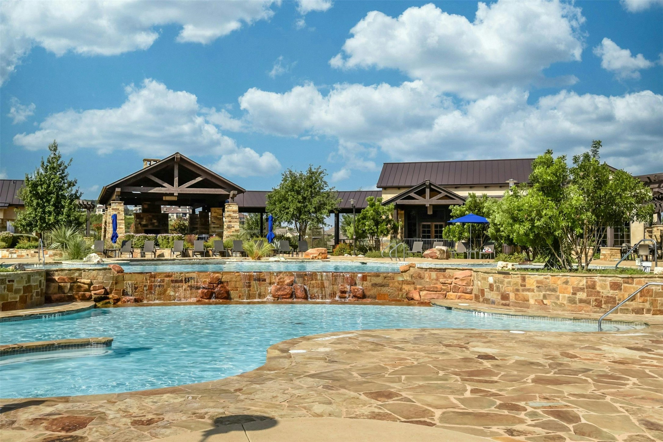 19113 Freeman Circle Austin, TX 78738 - Photo 34 of 37 Sweetwater Ranch -A resort-style swimming pool area features a rock waterfall, flagstone decking, and an inviting covered pavilion.