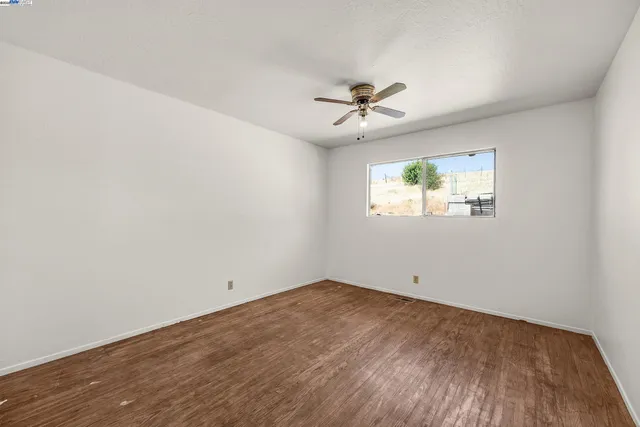 an empty room with a window and a ceiling fan
