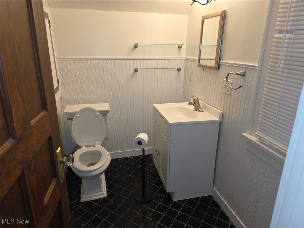 64 Sheldon Street Rittman, OH 44270 - Photo 8 of 37 Half bathroom with vanity, dark tile patterned flooring, and wainscoting